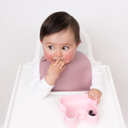 Little girl eating in her high chair wearing her pocket bib